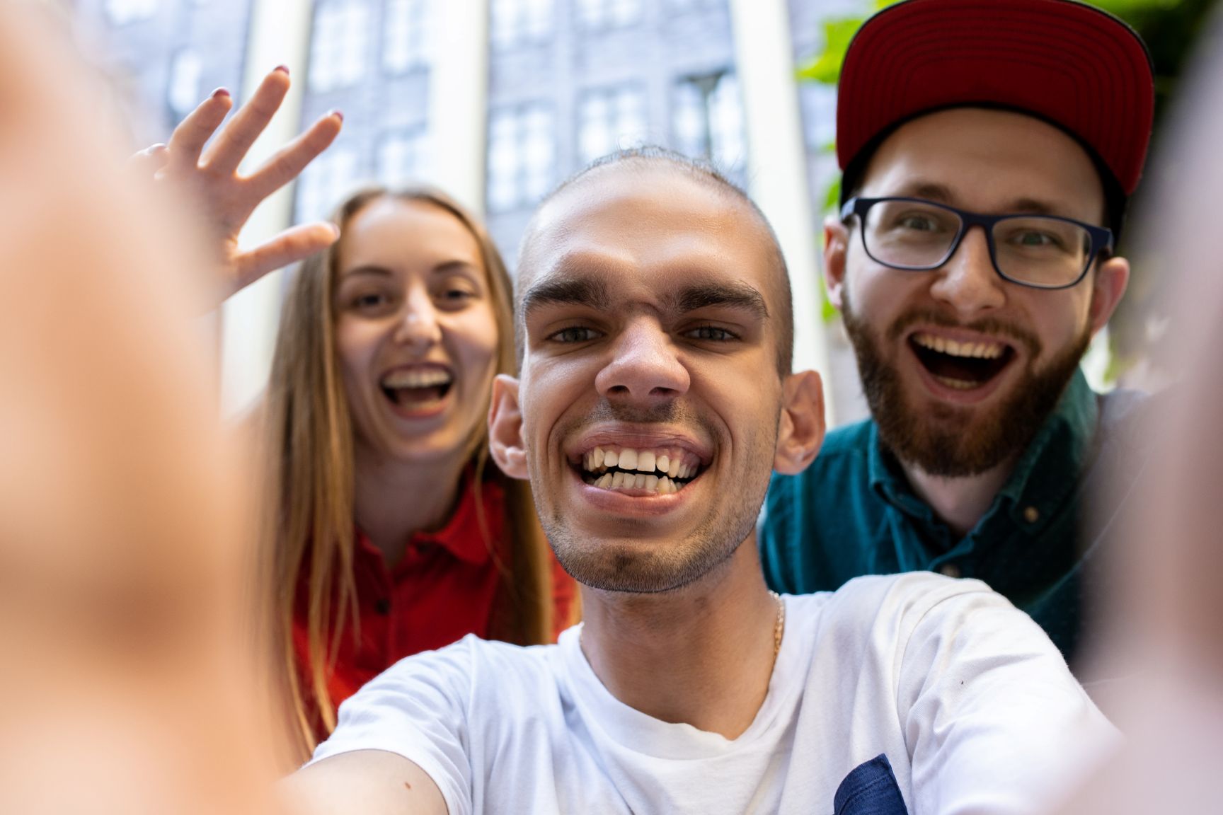 Group of friends taking selfie outside apartment.